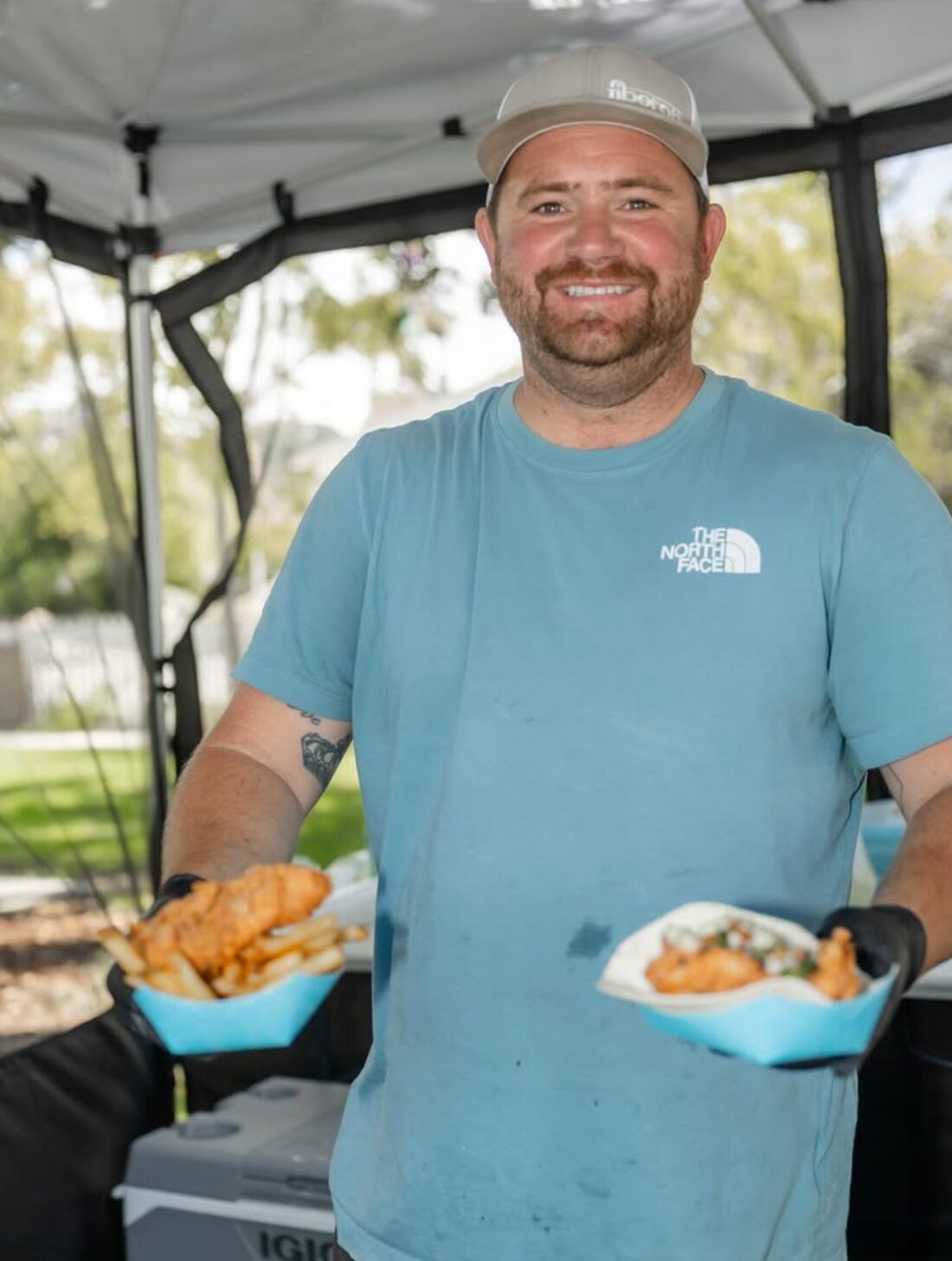 Cole at the catering tent holding plates of food