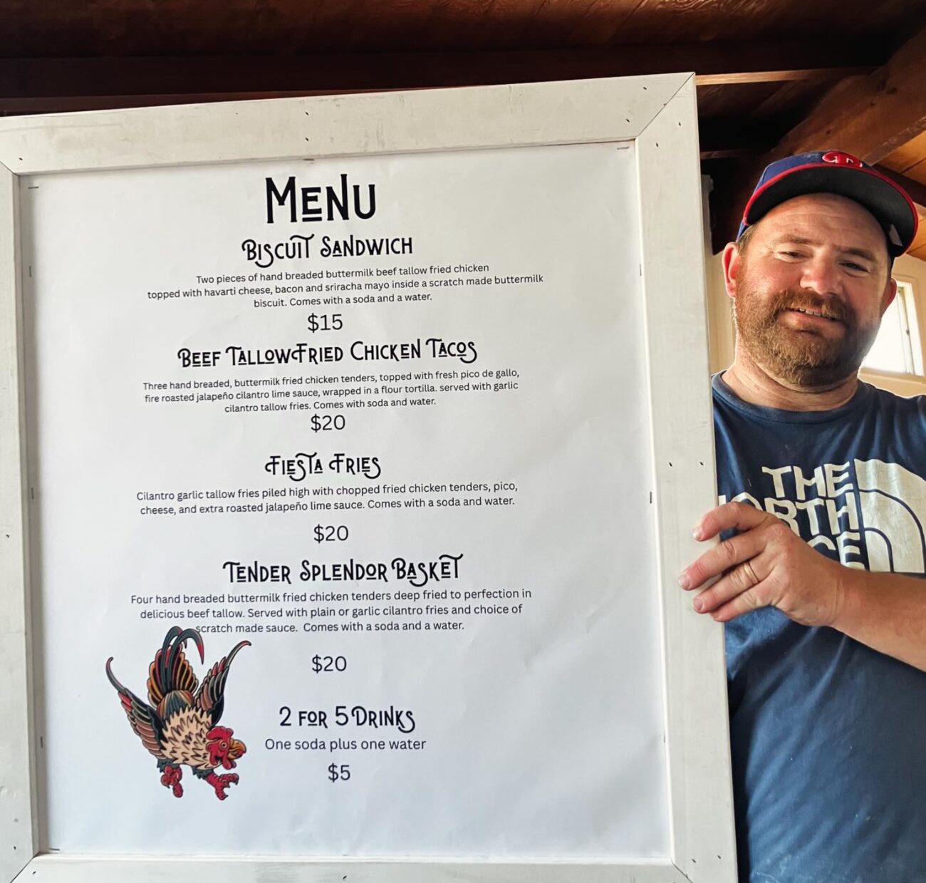 Cole standing beside the Coop de Grill menu board